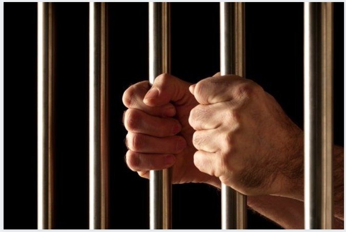 An inmate holding jail bars.