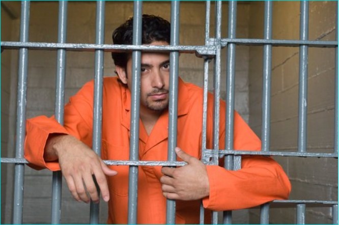 An inmate leaning on his jail cell bars