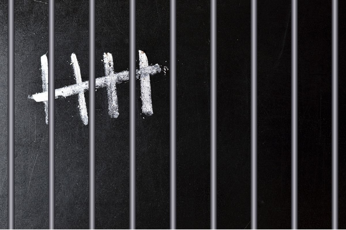 A 5-strike sign behind steels bars symbolizing a countdown of prison sentence.