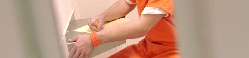 An inmate writing a letter to his pen pal.