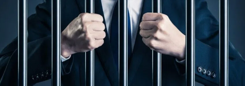 A white-collar worker grasping the prison bars.