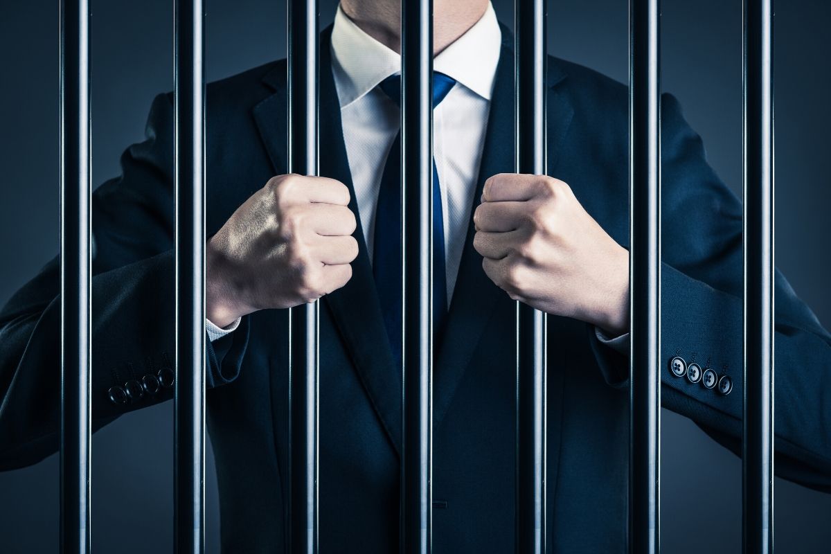 A white-collar worker grasping the prison bars.