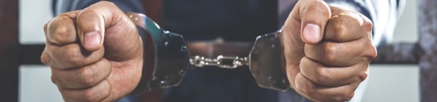 A man in handcuffs puts his hands through the bars.