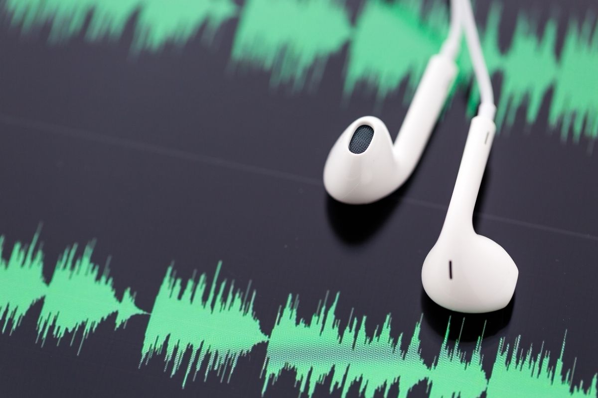 A pair of headphones on top of a screen showing audio waves.