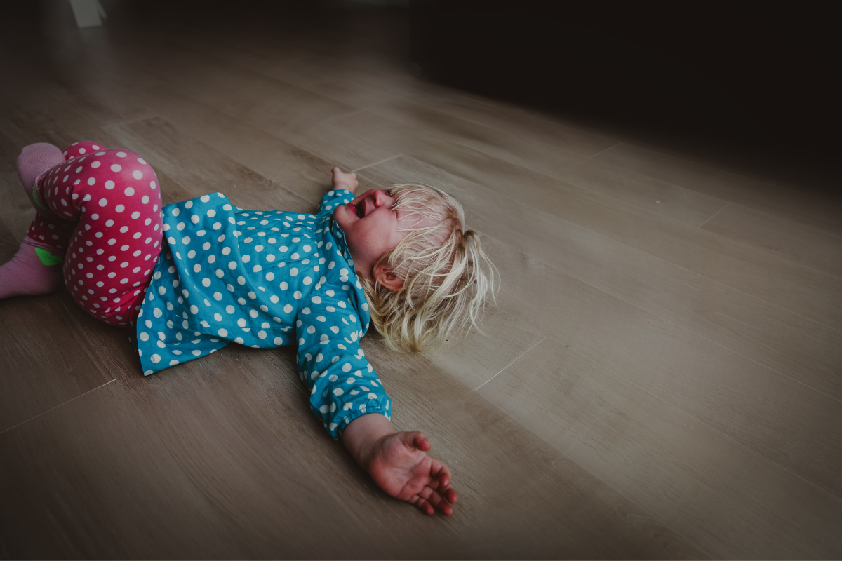 A crying child lying on the floor.