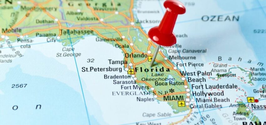 A map of Florida with a red push pin tacked to it.