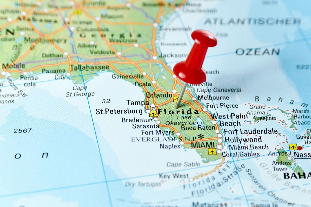 A map of Florida with a red push pin tacked to it.