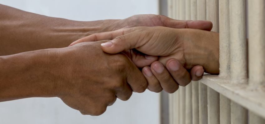 An inmate is holding the hands of his spouse while telling the benefits for spouses of incarcerated.