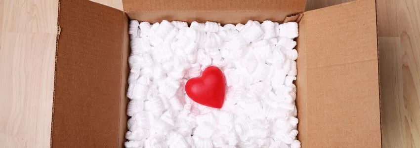 A box that carries care packages for inmates filled with packaging filler and one heart-shaped filler.