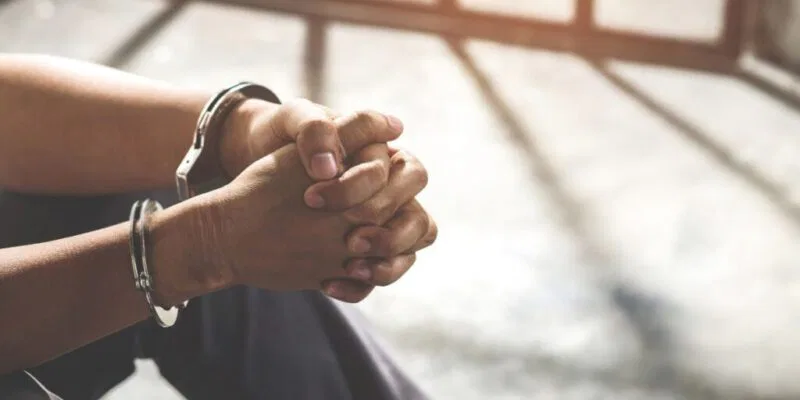 A prisoner in handcuffs waiting for care packages for inmates